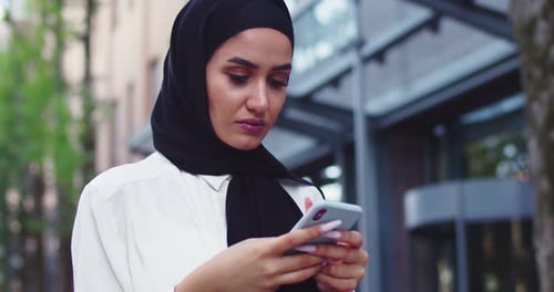 Close Up Portrait of Arabic Woman in Traditional Headscarves Looking at Phone and Smilingt Pretty