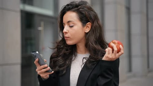 Woman Eating Apple While Using Mobile Phone