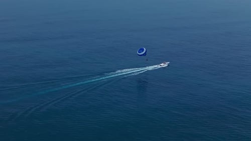 Flying with Parachute Behind a Boat Parasailing Drone View