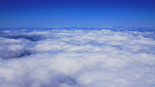A breathtaking aerial view from a plane as it glides above fluffy white clouds amidst the bright