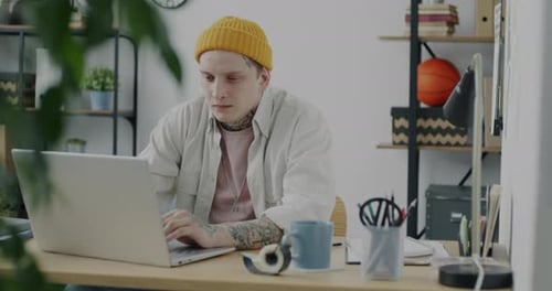 Porträt eines müden Geschäftsmannes, der mit einem Laptop arbeitet und dann die Arme ausstreckt und im Büro am Schreibtisch sitzt