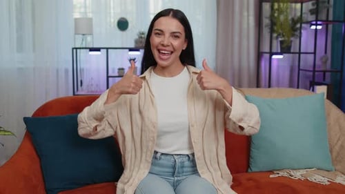 Smiling Woman Gives Thumbs Up on Couch