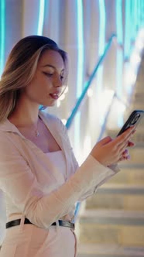 Woman Using Smartphone at Night in Urban Setting