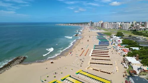 Aerial view of the beach and city of Miramar, waves breaking, buildings in the background. Drone sho