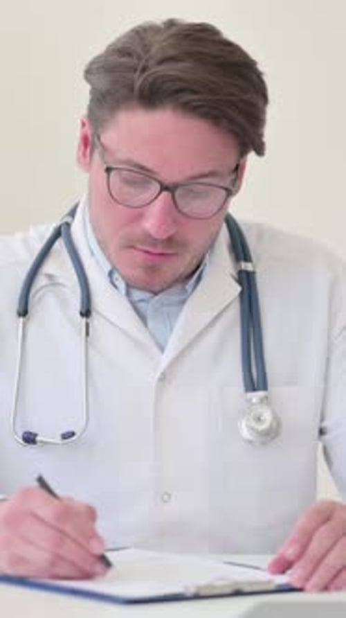 Doctor Writing on Chart in Office