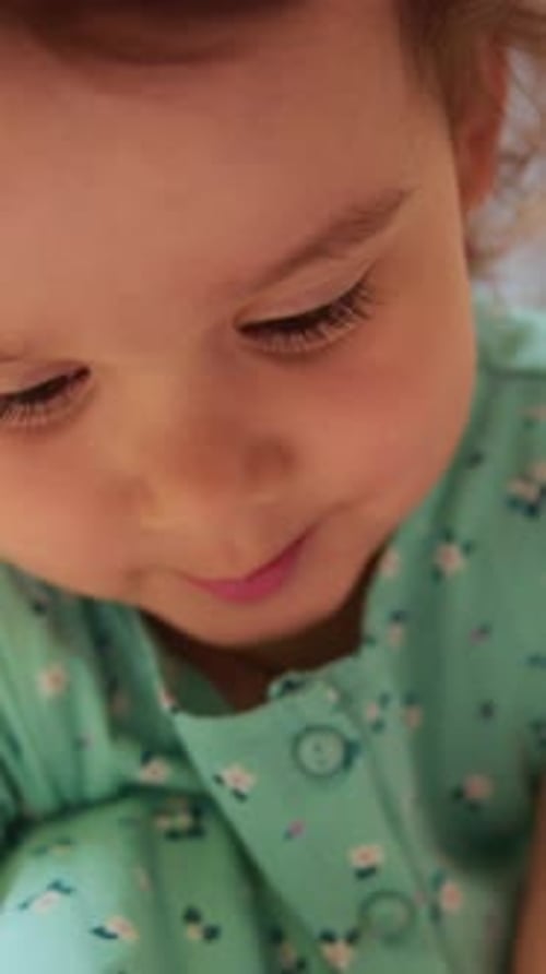 Joyeux bambin aux joues roses et aux yeux brillants, fille qui rit, vêtue d'une robe bleu sarcelle, naturelle