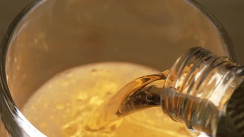 A cerveja é despejada de uma garrafa em um copo em câmera lenta a 240 fps.. Bolhas de cerveja e respingo de espuma