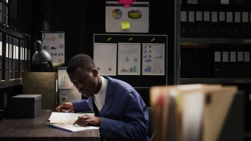 Office Workers Reviewing Paperwork in Dark Office