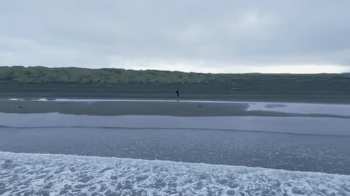 Person Walking At Stokksnes Beach In Iceland. - aerial orbit