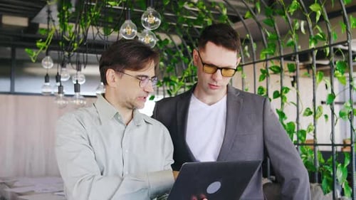 Businessmen Reviewing Laptop in Modern Workplace
