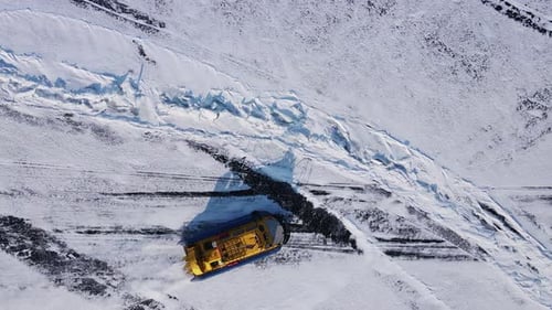 During Winter an Aerial View Shows a Snowplow Clearing Snow From a Road in Cold Conditions