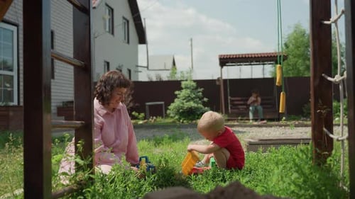 Woman and Child Play with Toy Truck in Yard