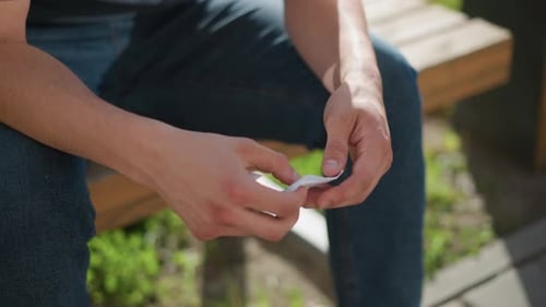 Close View of Hands Applying Nicotine Patch Outdoors in Sunlight