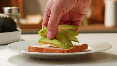 Hand Prepares Sliced Avocado on Toast Snack