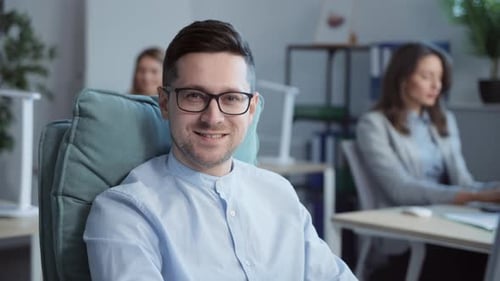 Nahaufnahme eines männlichen gutaussehenden Arbeiters mit schwarzer Brille, der auf einem bequemen Designer sitzt