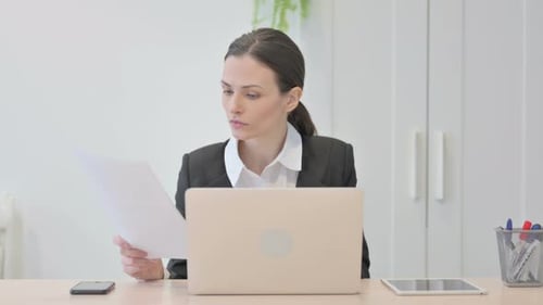 Joven empresaria que trabaja en una computadora portátil y documentos