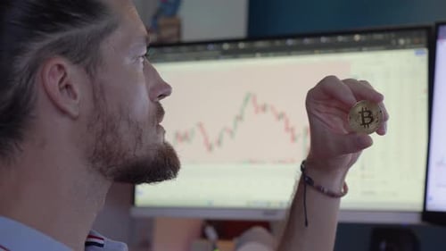 Nahaufnahme eines Mannes, der einen Bitcoin in der Hand hält und mit seinen Gewinnen an Kryptowährung zufrieden ist