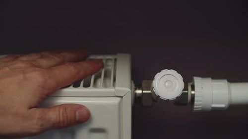 Hand Adjusts Radiator Temperature Control Indoors