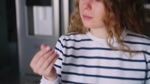 Close Up Footage of Young Woman Taking Pills with a Glass of Water at Modern Kitchen Curly Blonde