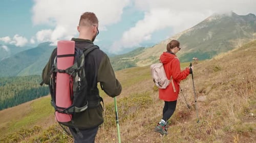 Rear View of Man and Woman Hikers Climbing Up on Mountain Slope in Hike