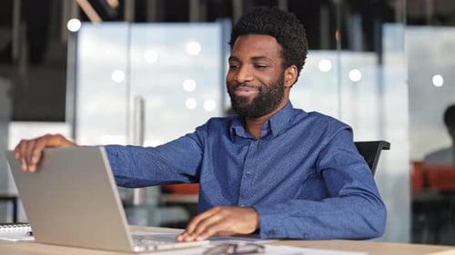 Young Businessman Finishes Work on Laptop Closes It and Relaxes in Office Chair