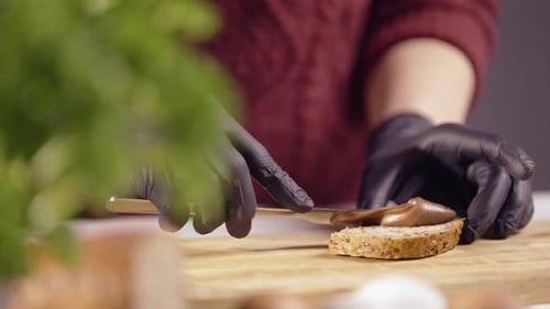 Étaler de la tartinade aux noisettes sur du pain de grains entiers — Gros plan sur la préparation du petit-déjeuner sucré