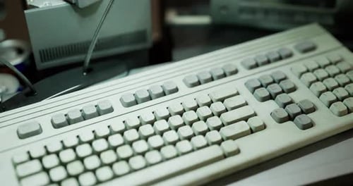 Old Computer Keyboard and Equipment on a Desk with Soft Lighting