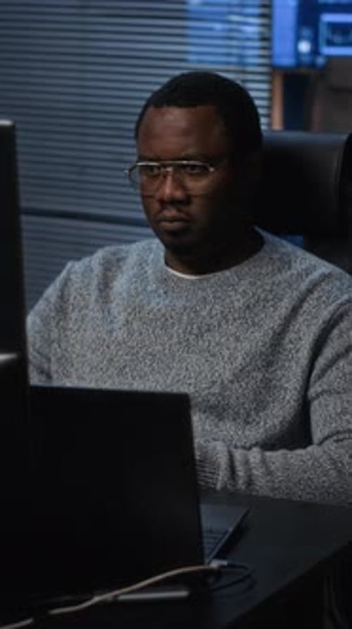 Vertical of Cybersecurity Specialist Working Alone at Computer in Dark Office