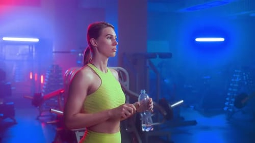 Woman Drinking Water in Colorful Gym
