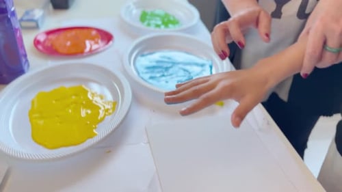 Child and teacher make handprint painting as a Mother’s Day gift