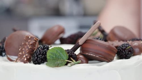 A close-up of the pastry chef rotating their finished cake with chocolate decorations on top.