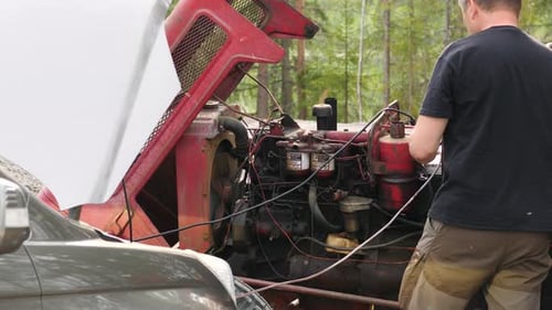 Static shot of a mechanic repairing an old tractor motor, on a sunny, summer day, in Ostrobothnia, F