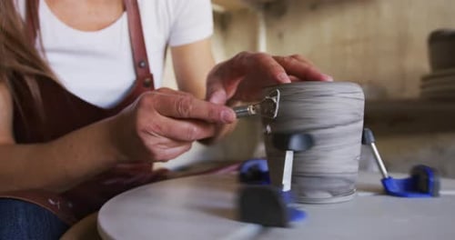 Female Potter Sitting at a Pottery Wheel in Her Art Studio Using