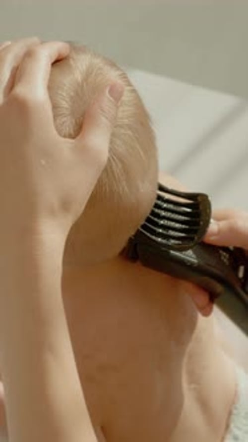 Vídeo vertical: Madre le corta el pelo a un niño pequeño por primera vez en casa