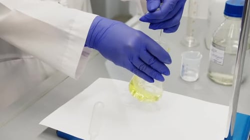 Gloved Hand Mixing Solution in Lab Flask