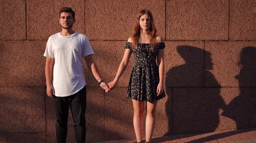 Couple Holding Hands in Front of Brick Wall