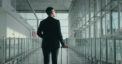 Man in Suit Walks with Suitcase in Airport