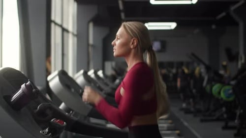 Young Caucasian Sportswoman Intensively Running on the the Treadmill in Indoor Fitness Club