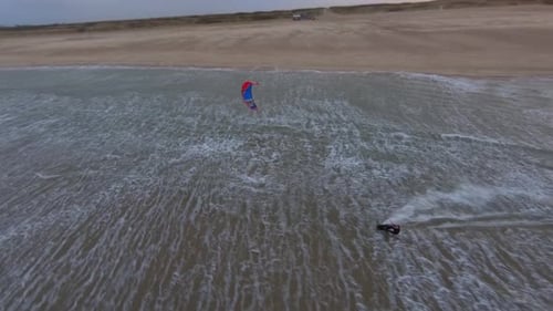 Fast aerial shot of a kitesurfer going through a lagoon in the North Sea.