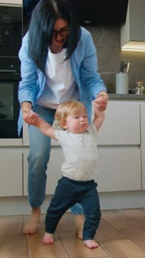 Caucasian Cute Little Baby Boy Child Learn to Walk with Mom in House Mother Holding Hands Baby Who
