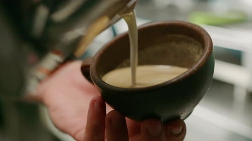 Barista making latte art in a cafe Male hands pouring steam of milk into a cup of Cappuccino