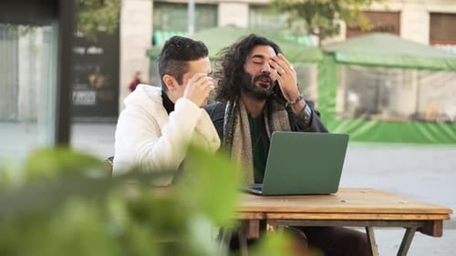 Young Men Working Together on Laptop in City