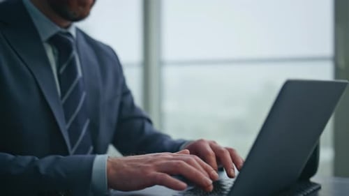 Man Typing on Laptop in Bright Modern Office