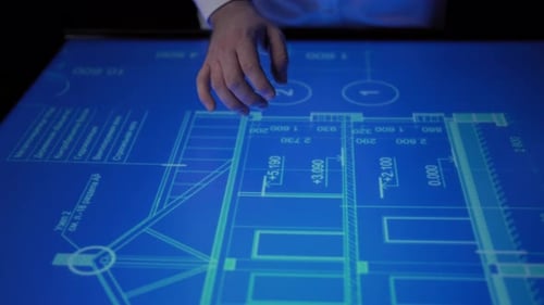 Man Discussing Important Details Pointing His Hand at Blueprint on Monitor