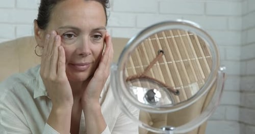 Woman Touches Face Looking in Mirror