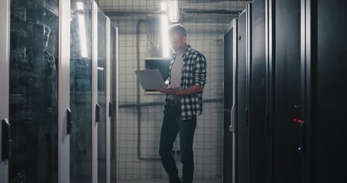 Man with Laptop in Data Center Server Room