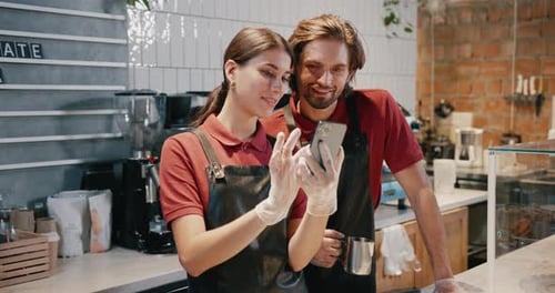 Baristas Looking at Mobile Phone in Cafe