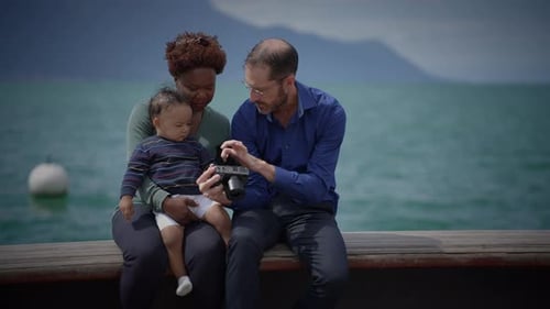 Happy Family with Infant Looking at Camera by Lake