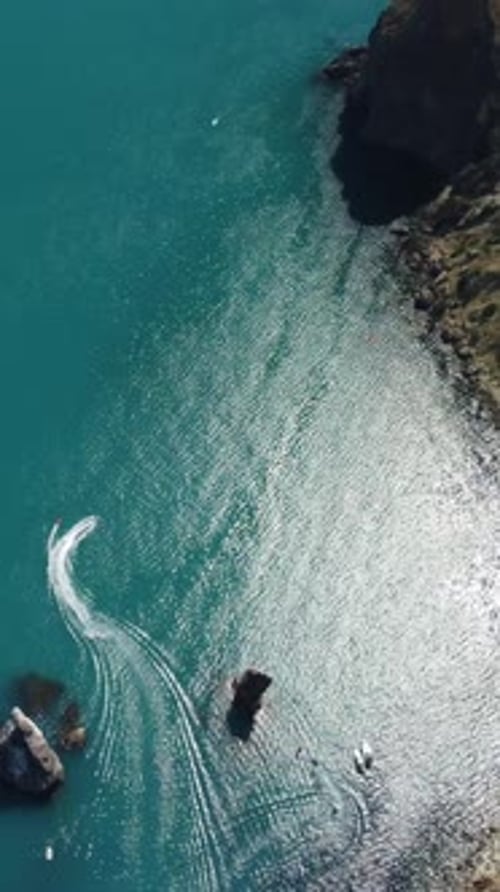 Câmera de visão aérea vertical da superfície da água do mar sobrevoa o mar calmo com costas rochosas vulcânicas