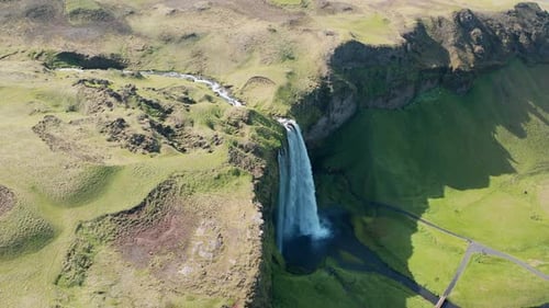 Zumbido hacia la cascada de Seljalandsfoss en un paisaje verde